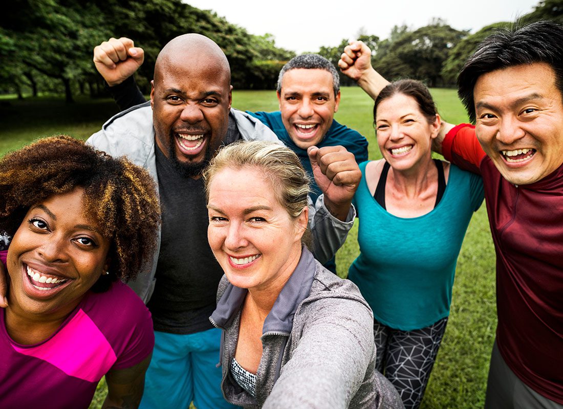 Employee Benefits - Diverse Group of Excited Mature Friends Having Fun Working Out Together Outside in the Park