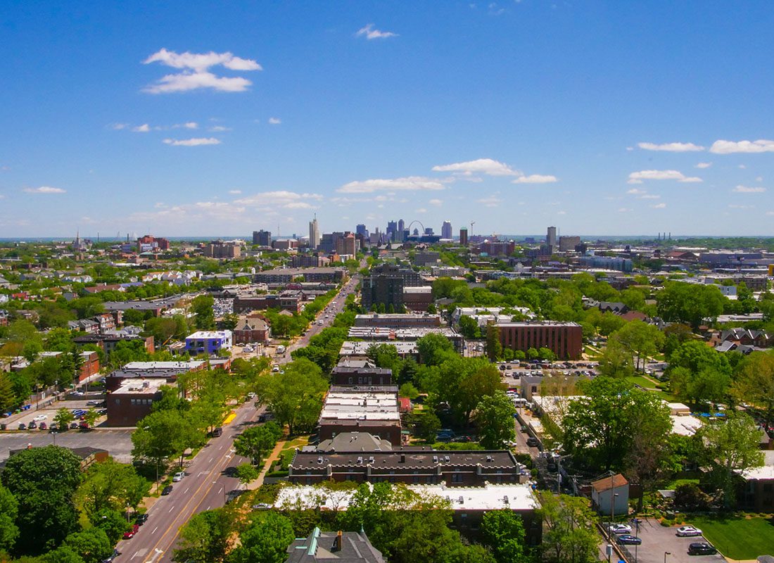 Fenton, MO - Aerial View of Homes and Commercial Buildings Surrounded by Green Trees in the Suburb of Fenton Missouri with City Skyline Views of Downtown St. Louis